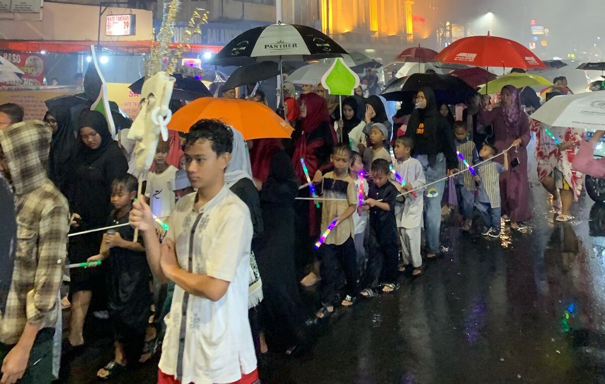 Doc.Peserta pawai obor berjalan menyusuri jalanan RW 03 sambil melantunkan shalawat. Meski hujan turun, semangat mereka tetap tinggi dalam menyambut bulan penuh berkah, dengan pengawalan dari aparat keamanan untuk memastikan kelancaran acara. (Kebon Kelapa, 27/2/2025 – Foto Dokumentasi: Maulana Syarif).