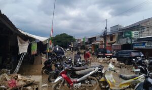 Doc. Kondisi banjir yang menggenangi ruas Jalan Pasar Bojong Kulur, Gunung Putri, Kabupaten Bogor, tampak menghambat aktivitas warga. Beberapa kendaraan sepeda motor terlihat terparkir di tengah genangan air, sementara pengendara dan pejalan kaki berusaha melewati jalan yang tergenang. (Bogor, 4/3/2025 – Foto Dokumentasi: M. Ismail).