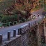 Doc. Jembatan perbatasan antara Desa Kaduagung dan Karangkancana di Kabupaten Kuningan, yang menjadi lokasi kecelakaan tunggal pada 19 Maret 2025. Terlihat kondisi jalan yang menurun tajam dengan pagar besi pengaman di sisi jembatan. Seorang pengendara sepeda motor tampak melintas di jalur tersebut. Warga setempat mengusulkan peninggian pagar besi guna meningkatkan keselamatan pengguna jalan. (Foto Dokumentasi: Muh. Ismail).