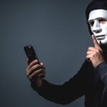 Doc. Gambar Ilustrasi ini menggambarkan seorang individu bertopeng yang menggunakan perangkat seluler, melambangkan ancaman kejahatan siber dan penipuan daring yang semakin marak menjelang musim mudik. Ilustrasi ini merepresentasikan berbagai modus penipuan tiket perjalanan yang sering terjadi, seperti penipuan melalui situs palsu, harga tiket yang terlalu murah, serta praktik calo ilegal. Dalam konteks mudik Lebaran 2025, masyarakat diimbau untuk lebih berhati-hati dalam melakukan transaksi secara daring guna menghindari kerugian akibat kejahatan digital. Catatan: Gambar ini merupakan ilustrasi konseptual yang dibuat untuk mendukung pemahaman tentang ancaman keamanan selama mudik dan tidak menggambarkan kejadian nyata di lokasi atau waktu tertentu. (Gambar:NR).