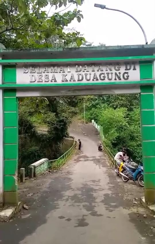 Doc. Gerbang masuk Desa Kaduagung, Kecamatan Karangkancana, Kabupaten Kuningan (siang hari), dengan latar belakang jembatan yang menjadi sorotan warga terkait minimnya penerangan jalan. Warga berharap pemerintah segera menangani permasalahan ini demi keselamatan bersama. (Kuningan, Jawa Barat, 4/4/2025 – Foto Dokumentasi: Muh. Ismail).