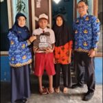 Doc. Kepala SMP Negeri 2 Banyuwangi, Dewi Astuti (kiri), menyerahkan seragam gratis kepada calon siswa jalur afirmasi di Kelurahan Sobo, Kecamatan Banyuwangi, didampingi wali murid dan guru sekolah, Selasa (20/5/2025). (Foto Dokumentasi: Ari Bagus. P).
