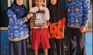 Doc. Kepala SMP Negeri 2 Banyuwangi, Dewi Astuti (kiri), menyerahkan seragam gratis kepada calon siswa jalur afirmasi di Kelurahan Sobo, Kecamatan Banyuwangi, didampingi wali murid dan guru sekolah, Selasa (20/5/2025). (Foto Dokumentasi: Ari Bagus. P).