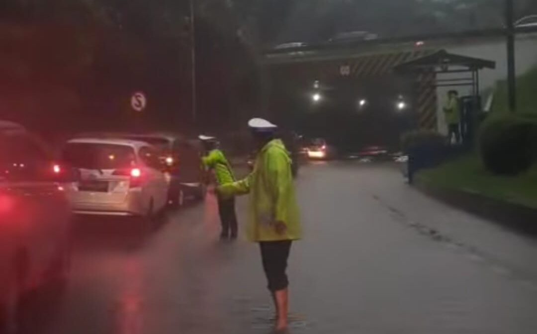 Doc. Seorang petugas kepolisian lalu lintas mengatur arus kendaraan yang tersendat akibat genangan air di Terowongan Cawang, Jakarta Timur, arah Tol Wiyoto Wiyono, Minggu (6/7/2025). Genangan setinggi sekitar 30 cm menyebabkan kemacetan panjang karena hanya satu lajur yang bisa dilalui kendaraan. Situasi diperparah oleh hujan deras yang masih berlangsung. (Foto Dokumentasi: TMC Polda Metro Jaya).