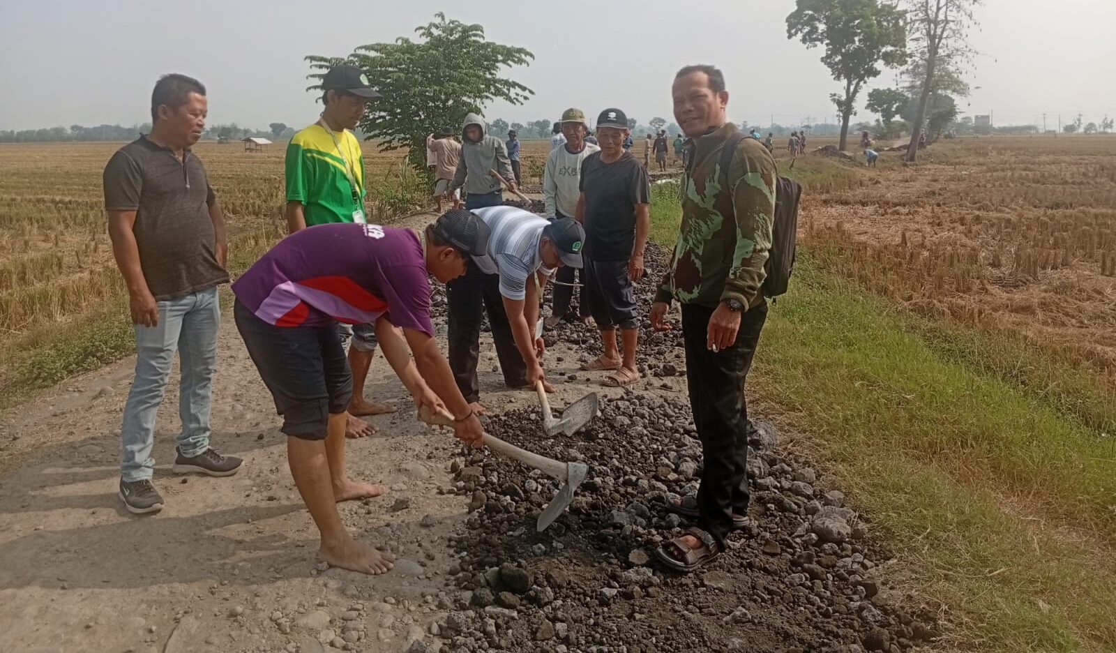 Doc. Sejumlah tokoh masyarakat, perangkat desa, dan pemuda turut serta dalam kegiatan gotong royong perbaikan jalan di tengah areal persawahan. Perbaikan jalan dilakukan manual dengan alat seadanya, mencerminkan semangat kebersamaan di tengah keterbatasan. (Foto: Soleh Hadi Mustofa).