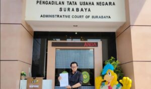 Doc. Eko Wahyu Pramono berdiri di depan Pengadilan Tata Usaha Negara (PTUN) Surabaya sambil menunjukkan berkas dokumen gugatan yang telah didaftarkannya. (Foto: Ismail).
