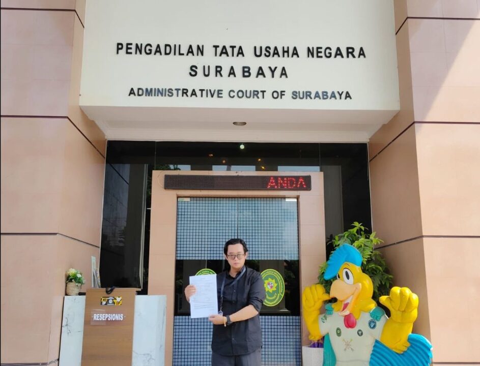 Doc. Eko Wahyu Pramono berdiri di depan Pengadilan Tata Usaha Negara (PTUN) Surabaya sambil menunjukkan berkas dokumen gugatan yang telah didaftarkannya. (Foto: Ismail).