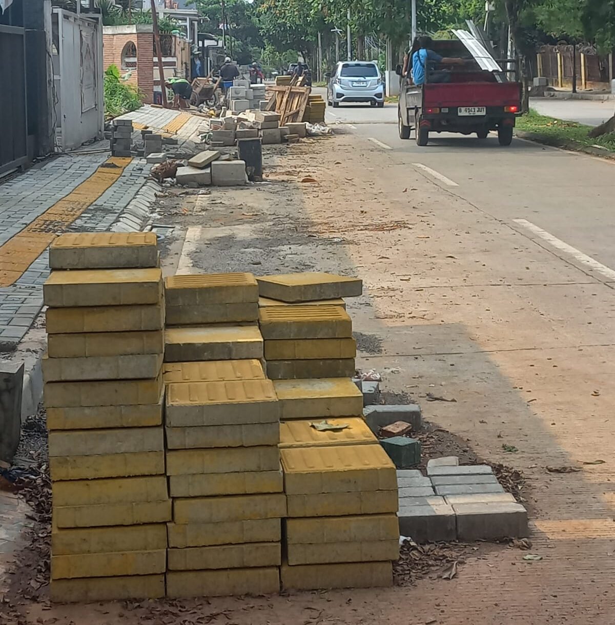 Doc. Material proyek berupa paving block, tanah galian, dan perlengkapan kerja tampak diletakkan di bahu jalan Jl. Ambon tanpa pagar pengaman maupun rambu keselamatan. Kondisi ini membuat jalur kendaraan menyempit dan meningkatkan risiko kecelakaan, terutama pada malam hari ketika penerangan sangat minim. (Foto: Moh. Ismail).