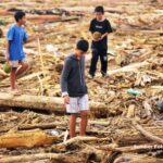 Doc. Sejumlah anak tampak berjalan di antara hamparan material kayu dan sampah yang terbawa arus banjir bandang. Mereka terlihat mencari barang yang masih dapat diselamatkan di tengah puing-puing tersebut. (Sumber Foto: KOMPAS.COM).