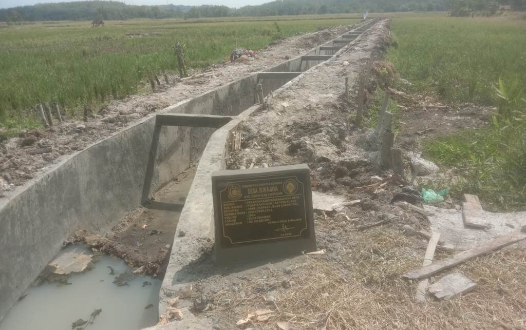 Doc. Kondisi proyek saluran pembuangan air limbah (SPAL) di area persawahan Desa Sukajaya, Kecamatan Cimahi, Kabupaten Kuningan, tampak tengah dalam tahap pembangunan. Terlihat papan informasi proyek terpasang di lokasi sebagai penanda kegiatan yang bersumber dari anggaran Dana Desa. (Foto: Moh. Ismail).