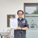 Doc. Eko Wahyu Pramono, S.Ak., saat menunjukkan bukti tanda terima laporan usai melaporkan dugaan promosi judi online terselubung ke SPKT Polda Jawa Timur, Surabaya, Selasa (30/12/2025). (Foto: KawanJariNews.com).
