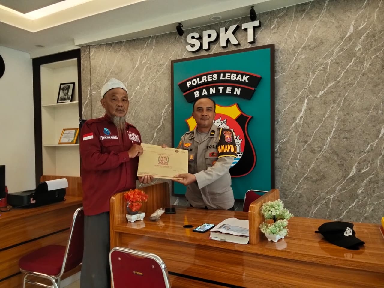 Doc. Fam Fuk Tjhong (kiri) saat menyerahkan berkas laporan pengaduan kepada petugas Sentra Pelayanan Kepolisian Terpadu (SPKT) Polres Lebak, Banten, terkait dugaan pernyataan bermuatan SARA yang diduga dilakukan oleh oknum anggota DPRD Kabupaten Lebak. (Foto: Mo. Ismail).