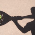 Doc. Ilustrasi bayangan seorang pemain padel yang bersiap memukul bola di lapangan. Pantulan cahaya membentuk siluet raket dan bola di permukaan lapangan, menggambarkan dinamika serta intensitas olahraga padel yang tengah berkembang di kawasan perkotaan. (NR).