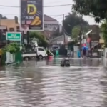 Doc. Genangan air merendam ruas jalan di kawasan permukiman setelah hujan dengan intensitas tinggi mengguyur wilayah tersebut sejak malam sebelumnya. Dalam foto terlihat sejumlah warga melintas dengan berjalan kaki sambil mendorong sepeda motor yang mogok akibat terendam air. Kondisi ini menunjukkan terganggunya aktivitas dan mobilitas masyarakat di tengah banjir yang melanda kawasan tersebut. (Foto: FERADI WPI Official).