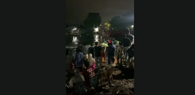 Doc. Tangkapan layar dari video dokumentasi memperlihatkan suasana di lokasi pencarian anak laki-laki yang dilaporkan tenggelam di Sungai Kayu Tangi, kawasan Parak Pasar Kasturi, Banjarmasin, Kamis (19/3/2026). Warga, relawan, dan aparat kepolisian tampak masih berada di sekitar bantaran sungai untuk memantau proses pencarian korban. (Sumber Foto: Tangkapan layar video warga).