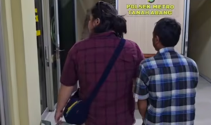 Doc. Tampak belakang terduga pelaku pembakaran angkot (sisi kanan) saat dibawa petugas (sisi kiri) dan diamankan setibanya di kantor kepolisian untuk menjalani pemeriksaan lebih lanjut.