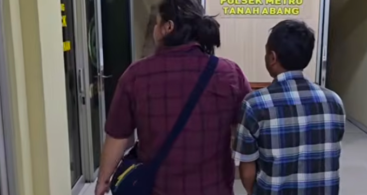 Doc. Tampak belakang terduga pelaku pembakaran angkot (sisi kanan) saat dibawa petugas (sisi kiri) dan diamankan setibanya di kantor kepolisian untuk menjalani pemeriksaan lebih lanjut.