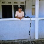 Doc. Seorang warga berdiri di depan rumahnya sambil menunjukkan kondisi tembok yang retak akibat guncangan gempa bumi yang mengguncang wilayah Bitung dan sekitarnya, Kamis (2/4/2026).