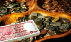 Doc. Ilustrasi uang rupiah lama, dengan latar belakang uang logam berbagai emisi lama dan tampak di bagian depan uang kertas pecahan Rp100 edisi lama sebagai representasi uang yang telah dicabut dari peredaran oleh Bank Indonesia.