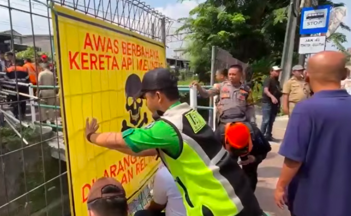Doc. Petugas memasang baliho peringatan di kawasan perlintasan kereta api liar jalur Tebet–Cawang, Jakarta Selatan, sebagai bagian dari upaya sosialisasi keselamatan dan rencana penertiban akses penyeberangan tidak resmi.