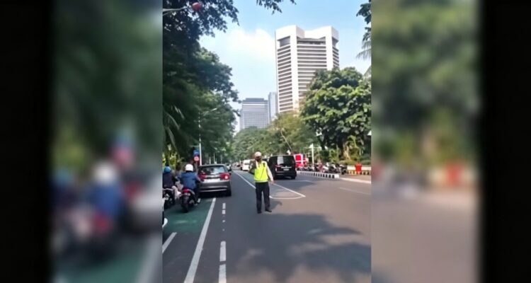 Doc. Tangkapan layar rekaman video yang beredar di media sosial memperlihatkan seorang anggota kepolisian berdiri di tengah badan jalan saat melakukan pengaturan lalu lintas sebelum insiden dugaan pemukulan terhadap kaca ambulans di kawasan Tanah Abang, Jakarta Pusat, Senin (6/7/2026).
