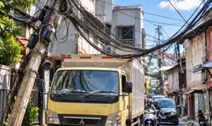 Doc. Kabel utilitas yang tampak semrawut dan menjuntai di antara bangunan serta melintas di atas badan jalan, dengan kendaraan harus melintas di bawah jaringan kabel tersebut.
