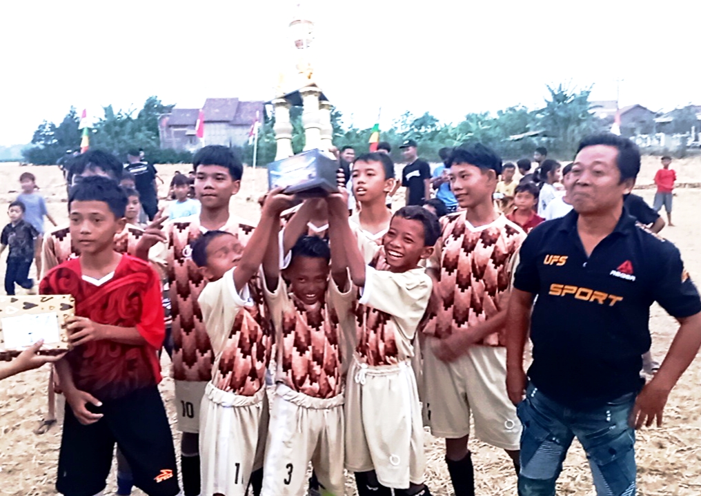 Doc. Salah satu peserta Turnamen Sepak Bola U14 Dronjong 2026 mengangkat trofi setelah pertandingan final di Stadion GBK, Dronjong, Pemalang, Minggu (4/10/2026). Bima FC dari RT 05 keluar sebagai juara setelah mengalahkan Real JR FC RT 03 dengan skor 2-0.