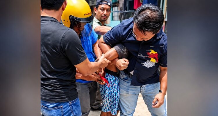 Doc. Petugas bersama sejumlah orang mengamankan seorang pria dalam pengungkapan kasus dugaan pencurian dengan kekerasan terhadap pengemudi ojek online di kawasan Tanjung Priok, Jakarta Utara. Dalam perkara ini, polisi telah menangkap dua orang yang diduga terlibat, sementara satu orang lainnya masih dalam pencarian. Foto merupakan ilustrasi hasil penyuntingan berbasis foto asli dan bukan dokumentasi tambahan dari lokasi kejadian.